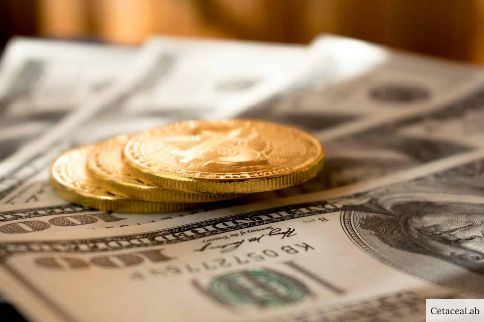 three round gold-colored coins on 100 US dollar banknotes