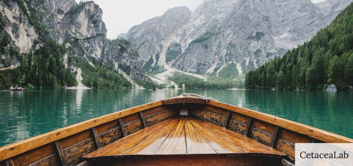 brown wooden boat moving towards the mountain