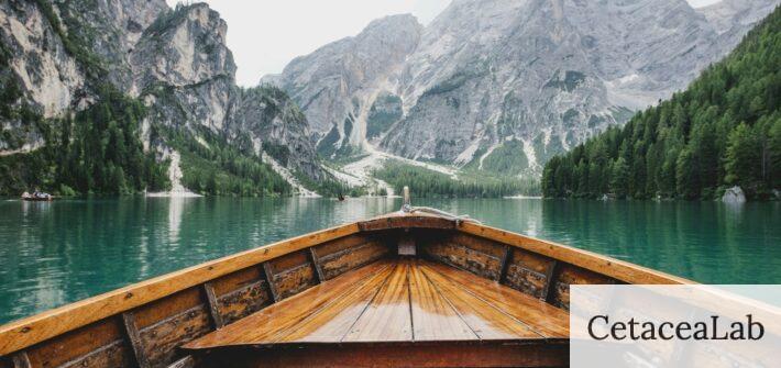 brown wooden boat moving towards the mountain