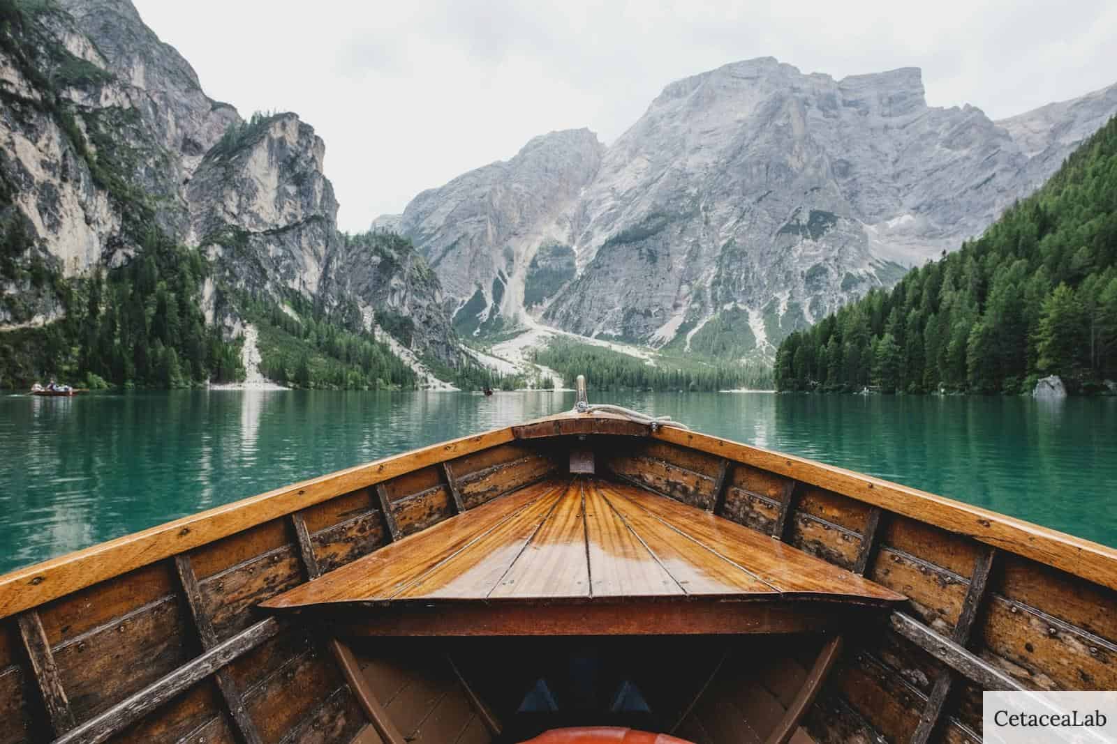 brown wooden boat moving towards the mountain